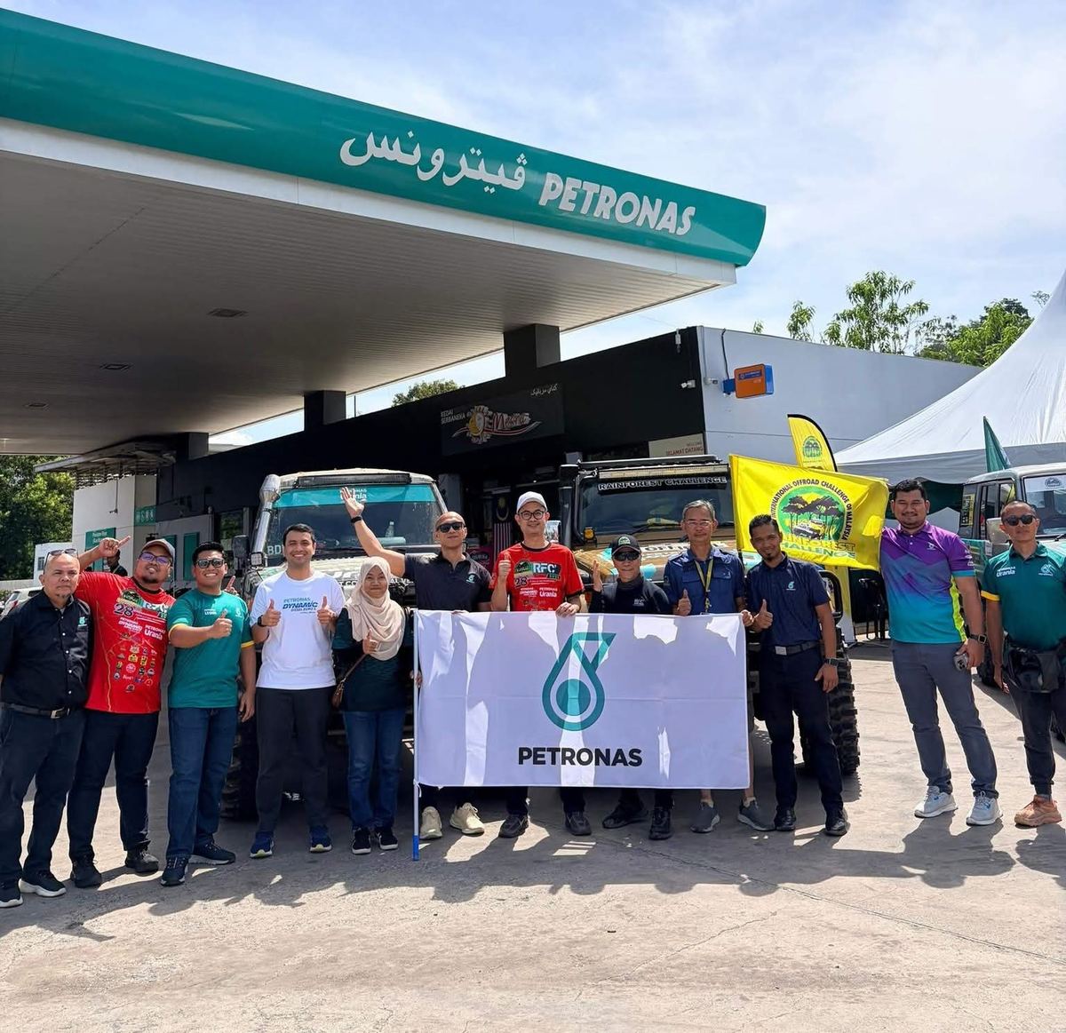 Participants and the PETRONAS team with a PETRONAS flag